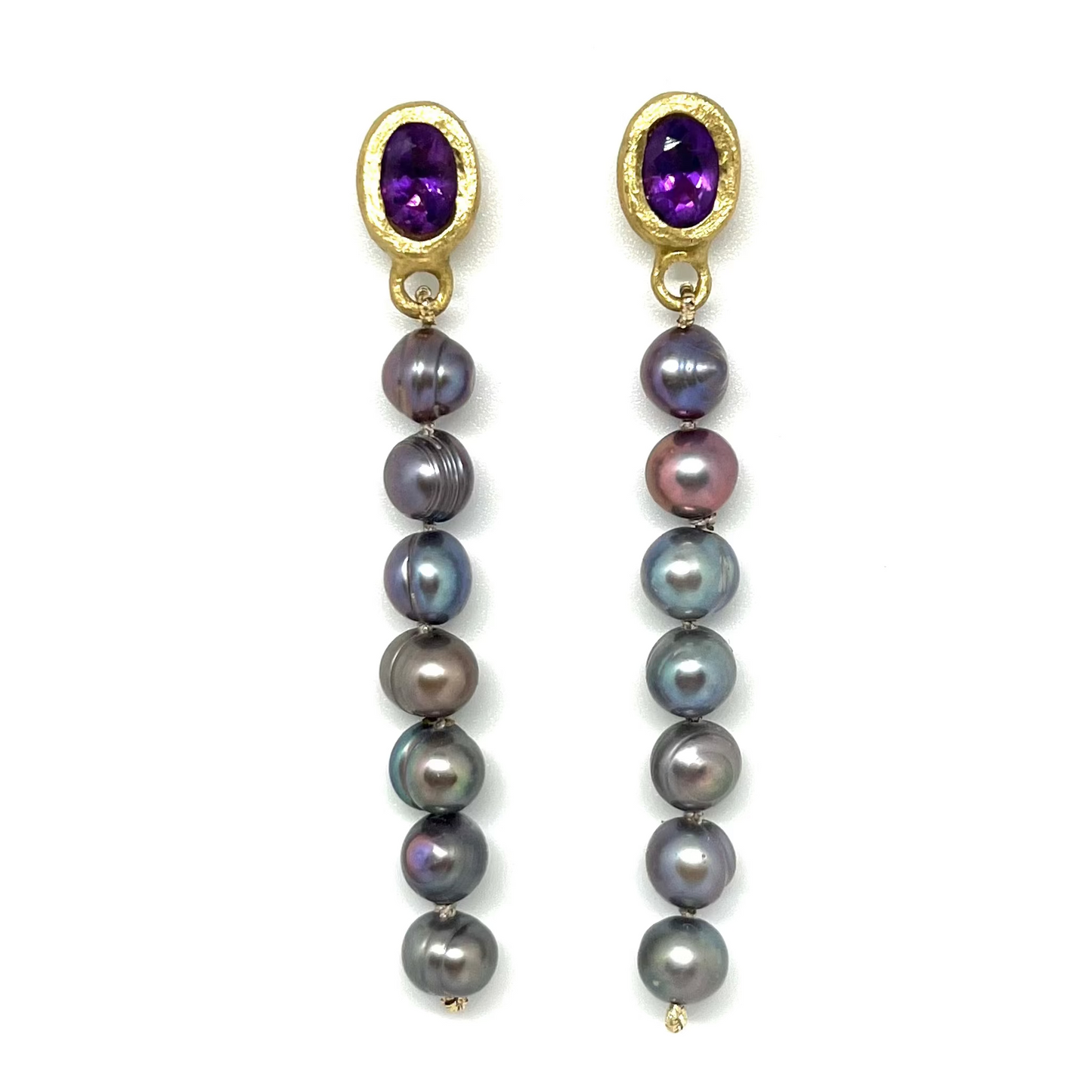 A pair of gold dangle earrings featuring oval purple amethyst tops and a vertical drop of dark gray and iridescent baroque pearls, set against a plain white background.