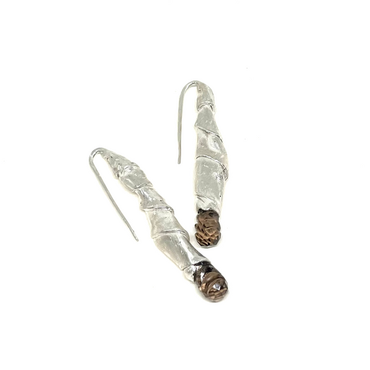 A pair of handmade silver dangle earrings with textured, wrapped silver bodies and small brown bead accents near the bottom, shown on a plain white background.